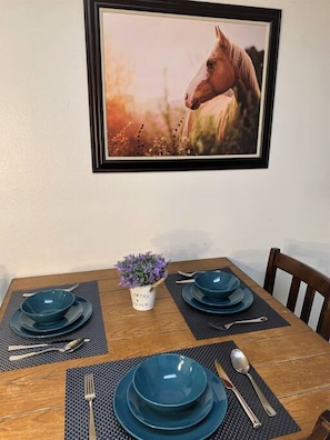 Enjoy meals in this dining area with a table for four, adorned with fine china and a charming potted plant.