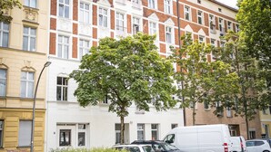 A multi-story building with a mix of brick and cream-colored facades, parked cars, and a tree in the foreground. - Großzügige Wohnung in Berlin Mitte für 6 Gäste (Berlin)