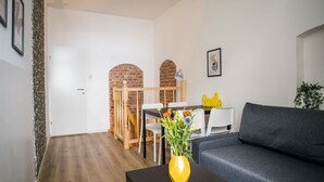 A modern living room with a grey sofa, a wooden dining table, and a yellow vase with flowers. - Großzügige Wohnung in Berlin Mitte für 6 Gäste (Berlin)