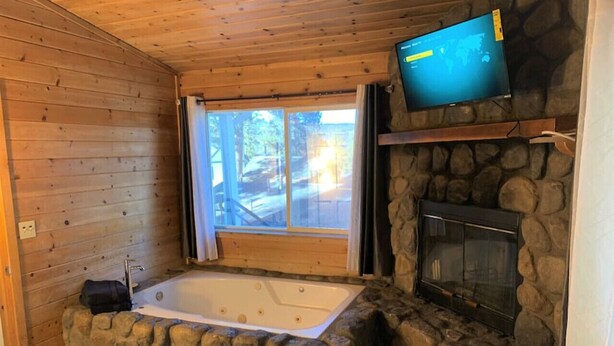 Una habitación con chimenea de piedra, un ventanal grande y techo de madera.
