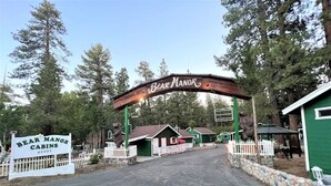 Les chalets de Bear Manor se distinguent par leur entrée en forme d’arche en bois, leur clôture blanche en piquets et leurs bâtiments aux couleurs vertes.