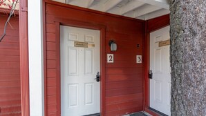 A building with two numbered doors, a tree, and a red exterior wall. - Spacious, Fun Family Cabin - Cozy Hollow Lodge #2 (Big Bear Lake)