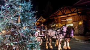 A Christmas tree with lights and a horse-drawn carriage in front of a building labeled "Village Inn." - Spacious, Fun Family Cabin - Cozy Hollow Lodge #2 (Big Bear Lake)