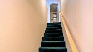 A staircase with a wooden handrail and carpeted steps leading to a doorway. - Spacious, Fun Family Cabin - Cozy Hollow Lodge #2 (Big Bear Lake)