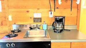 A compact kitchen with a gas stove, sink, and a microwave.
