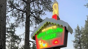 A sign for a rustic family cabin with a neon welcome sign and a vacancy indicator.