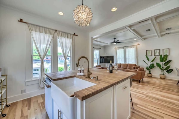 A spacious kitchen with a large island, wooden flooring, and a ceiling fan.