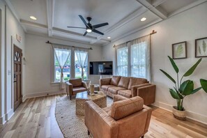 A spacious living room with a ceiling fan, leather sofas, a flat-screen TV, and large windows. - Luxury and Location With Hottub! (Fredericksburg)