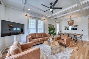 A spacious living room with a sectional sofa, a coffee table, and a dining area with a table and chairs.