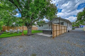 A single-story mobile home with a fenced backyard, a patio, and a small lawn. - Luxury and Location With Hottub! (Fredericksburg)