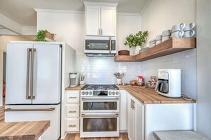 A compact kitchen with white cabinetry, a built-in microwave, a double oven, and a coffee maker on the countertop.