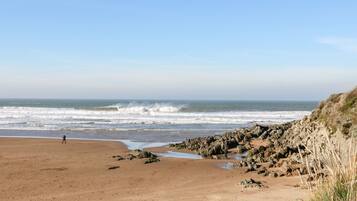 A beach with rocky terrain and a person walking.