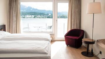 Ein Hotelzimmer mit einem Bett, einem roten Sessel, einem kleinen Tisch und einer Lampe.