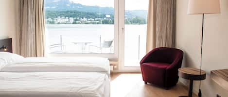 Una camera d'albergo con un letto, una poltrona rossa, un tavolino e una lampada.