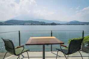 A balcony with a table and two chairs overlooking a lake with mountains in the background. - Hotel Seeburg (Lucerne)
