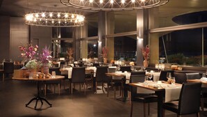 Un restaurant doté de nombreuses tables, de chaises et de grands lustres circulaires.