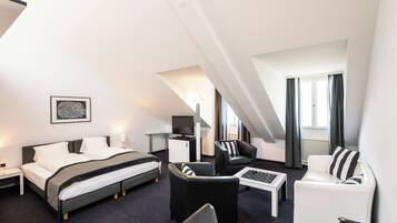 Ein modernes Hotelzimmer mit einem Bett, zwei Sesseln, einem Couchtisch, einem Schreibtisch und einem Fernseher.