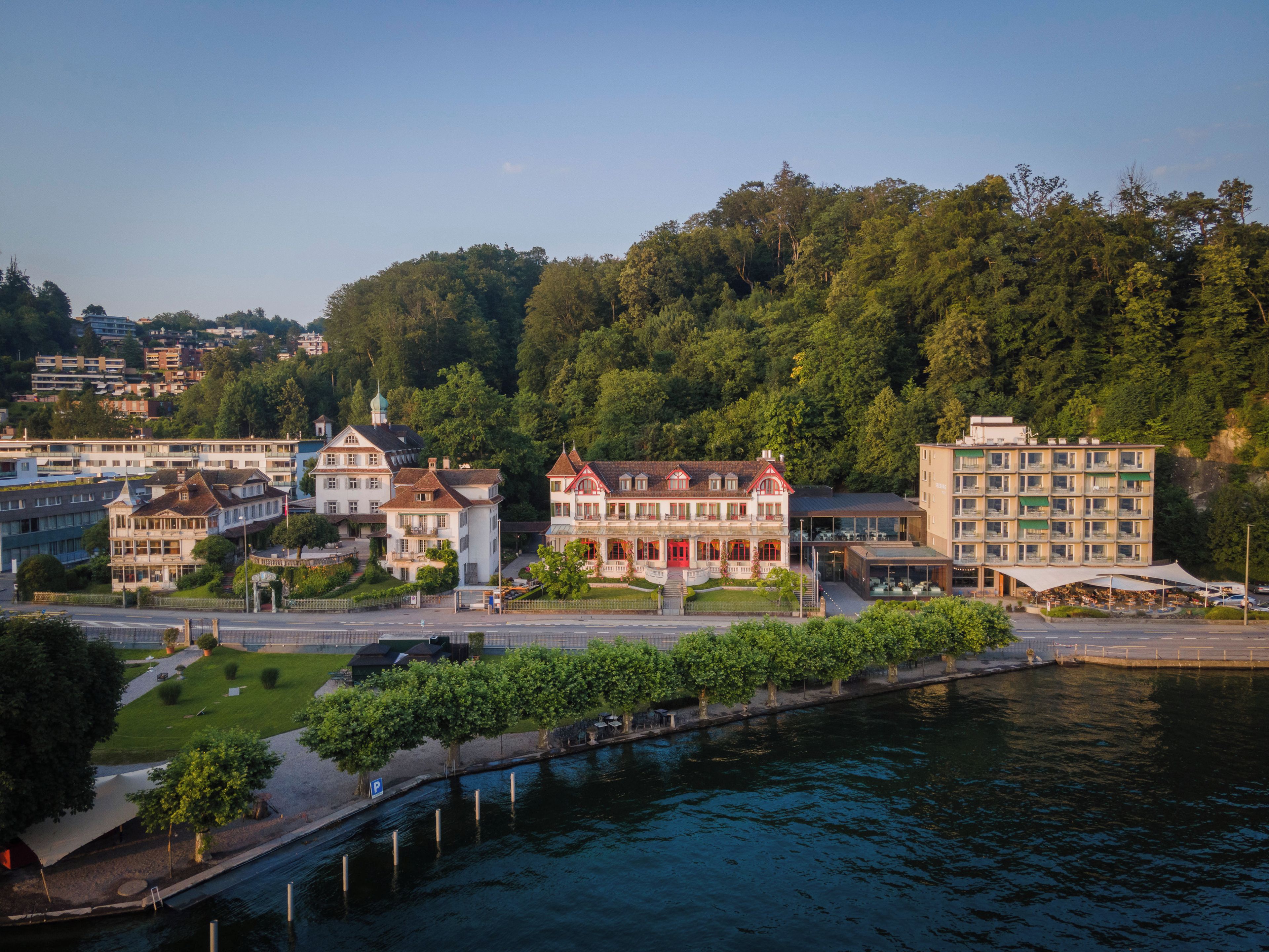 A riverside town with historic buildings, a bridge, and a forested hill.