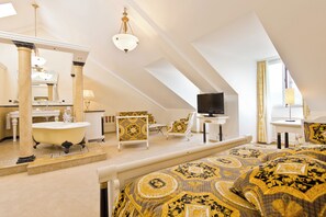 A high-ceilinged room with a large bed, a bathtub, a television, and a dining area. - Hotel Seeburg (Lucerne)