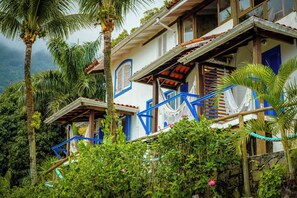 A multi-story building with blue accents, surrounded by lush greenery and palm trees. - VELINN Pousada 8 Ilhas (Ilhabela)