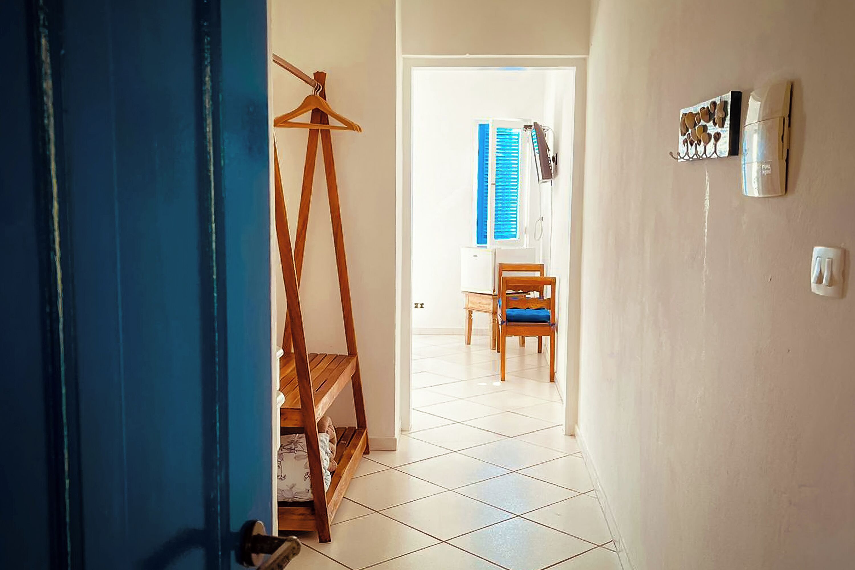 A hallway with a wooden easel, a chair, and a wall-mounted coffee machine.