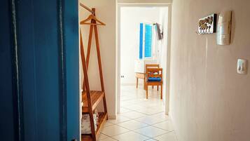 A hallway with a wooden easel, a chair, and a wall-mounted coffee machine.