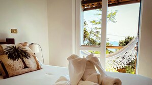 Una cama con toallas enrolladas y un almohadón con diseño de palmera.
