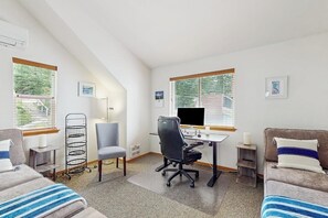 Moderni huone, jossa on työpöytä, kaksi tuolia, sohva, televisio ja ikkuna, jossa on sälekaihtimet.