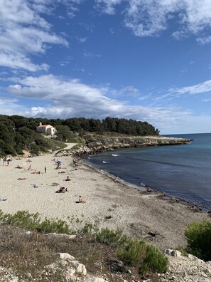 A beach with a small building, rocky shoreline, and clear blue sky. - Maisonnette la Couronne Près des Plages (Martigues)