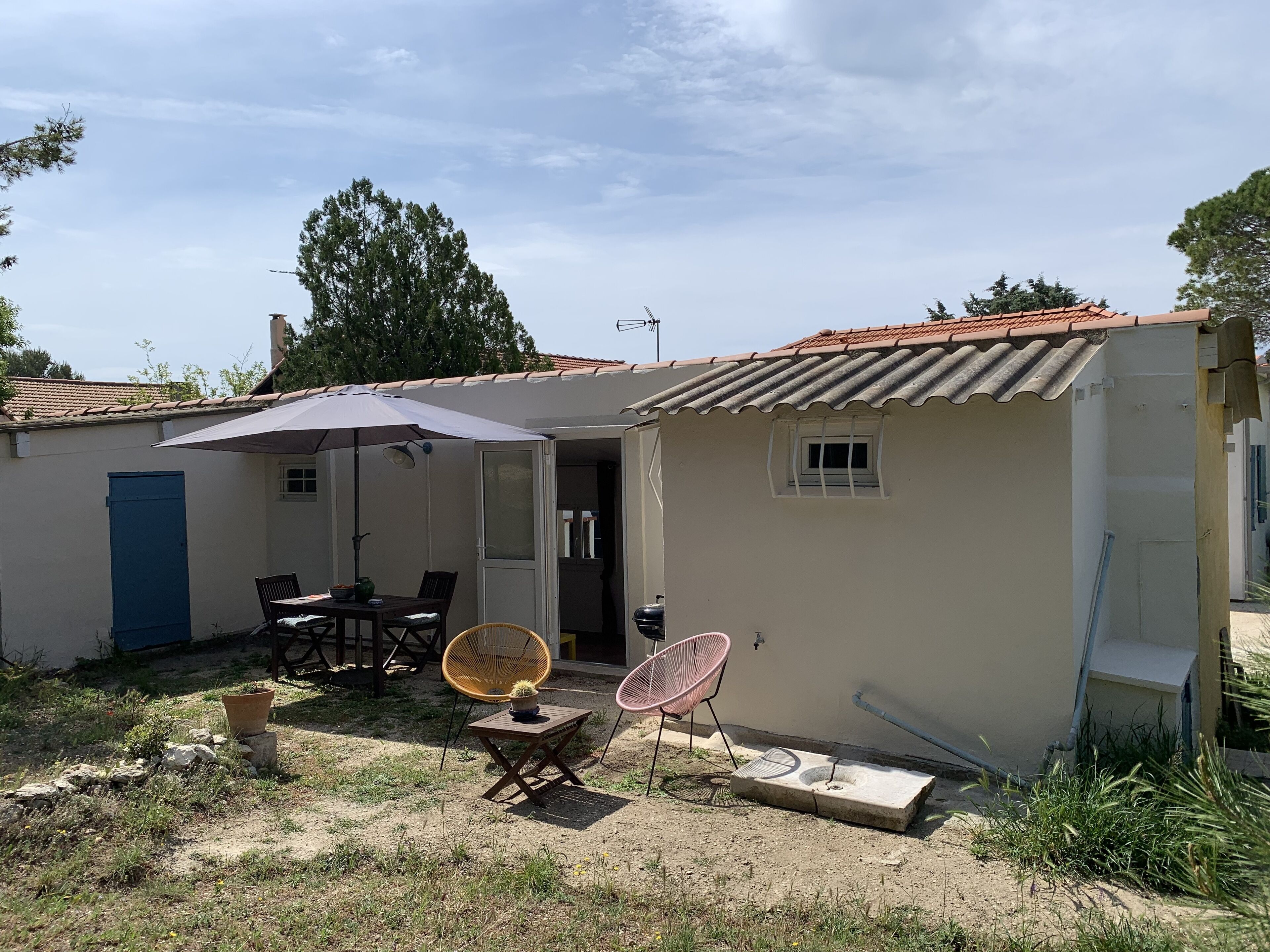 Un petit bâtiment d’un seul étage, doté d’un toit en tuiles, d’une terrasse avec une table et des chaises, et d’une petite fenêtre.