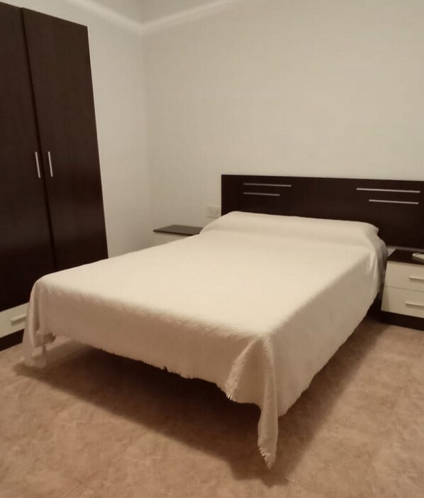 Une chambre à coucher comprenant un lit, une table de chevet, une commode et une armoire.