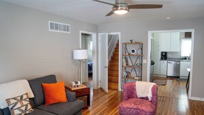 A living room with a gray sofa, an orange pillow, a purple armchair, a coffee table, and a ceiling fan. - 1742 Uptown | 3 bed, walk to Mayo St Marys Campus! (Rochester)