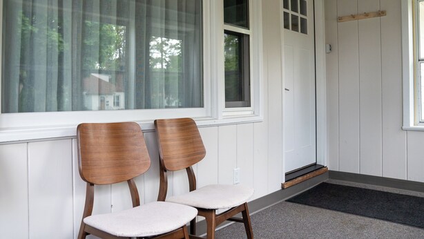A porch with two wooden chairs and a white door with a window above it. - 1742 Uptown | 3 bed, walk to Mayo St Marys Campus! (Rochester)