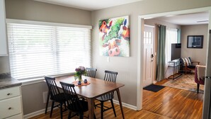 A dining area with a wooden table and chairs, a window with blinds, and a painting on the wall. - 1742 Uptown | 3 bed, walk to Mayo St Marys Campus! (Rochester)