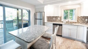 Uma cozinha moderna com bancada de granito, armários brancos e lava-louças embutida.