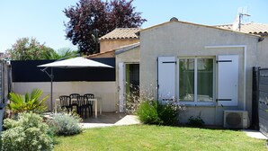 Una casa pequeña con un patio, una mesa y sillas, y un espacio exterior cubierto.
