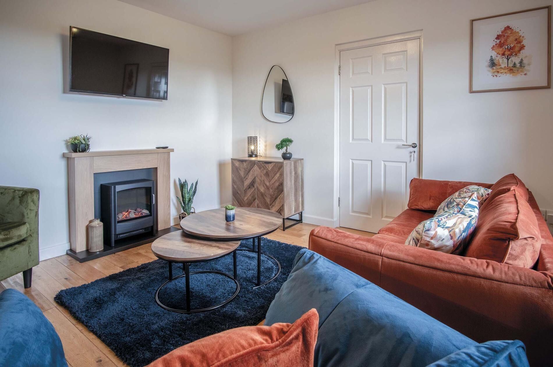 A living room with a fireplace, a sofa, a coffee table, and a TV mounted on the wall.