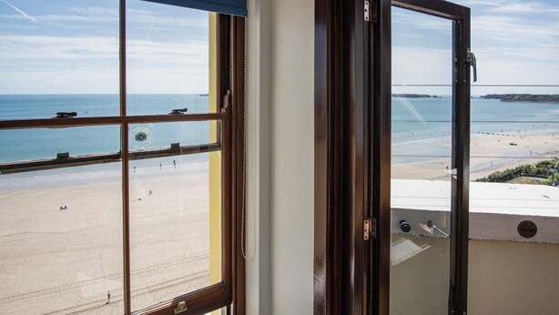 Blick vom Balkon auf einen Strand bei blauem Himmel.