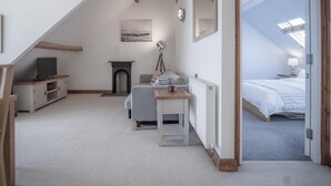 Ein gemütliches Schlafzimmer im Dachgeschoss mit Kamin, Fernseher und Bett.
