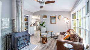 Een moderne woonkamer met een open haard, een plafondventilator, een bank en een eethoek.
