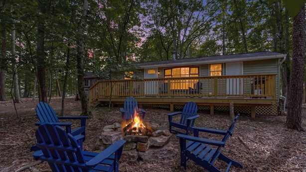 Een chalet met een terras, een vuurplaats en Adirondack stoelen.