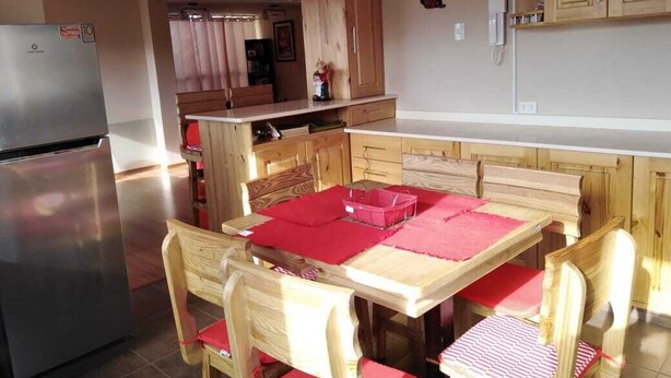 Une cuisine compacte avec des meubles en bois, un réfrigérateur en acier inoxydable et une table à manger agrémentée de sets de table rouges.