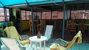 Un espace extérieur abrité, aménagé avec des chaises à structure métallique, une petite table ronde et un objet décoratif posé sur la table.