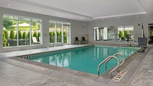 An indoor swimming pool with clear glass walls, a tiled floor, and a shallow area marked.
