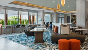 A modern hotel lobby with a large seating area, a bar, and a view of the outdoors.