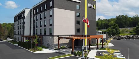 A modern hotel with a two-story structure, a covered entrance, and a parking area with designated spaces.