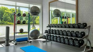 A gym with exercise equipment, including dumbbells and medicine balls, and a large mirror.