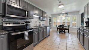 A modern kitchen with grey cabinetry, a stainless steel microwave, and a black stove.