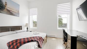 Relax in a stylish room with a made bed, flat-screen TV, and desk area.