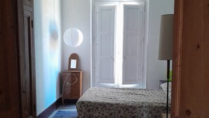 Ein Schlafzimmer mit einem Bett, einem Schminktisch, einem Spiegel und einer Tür.